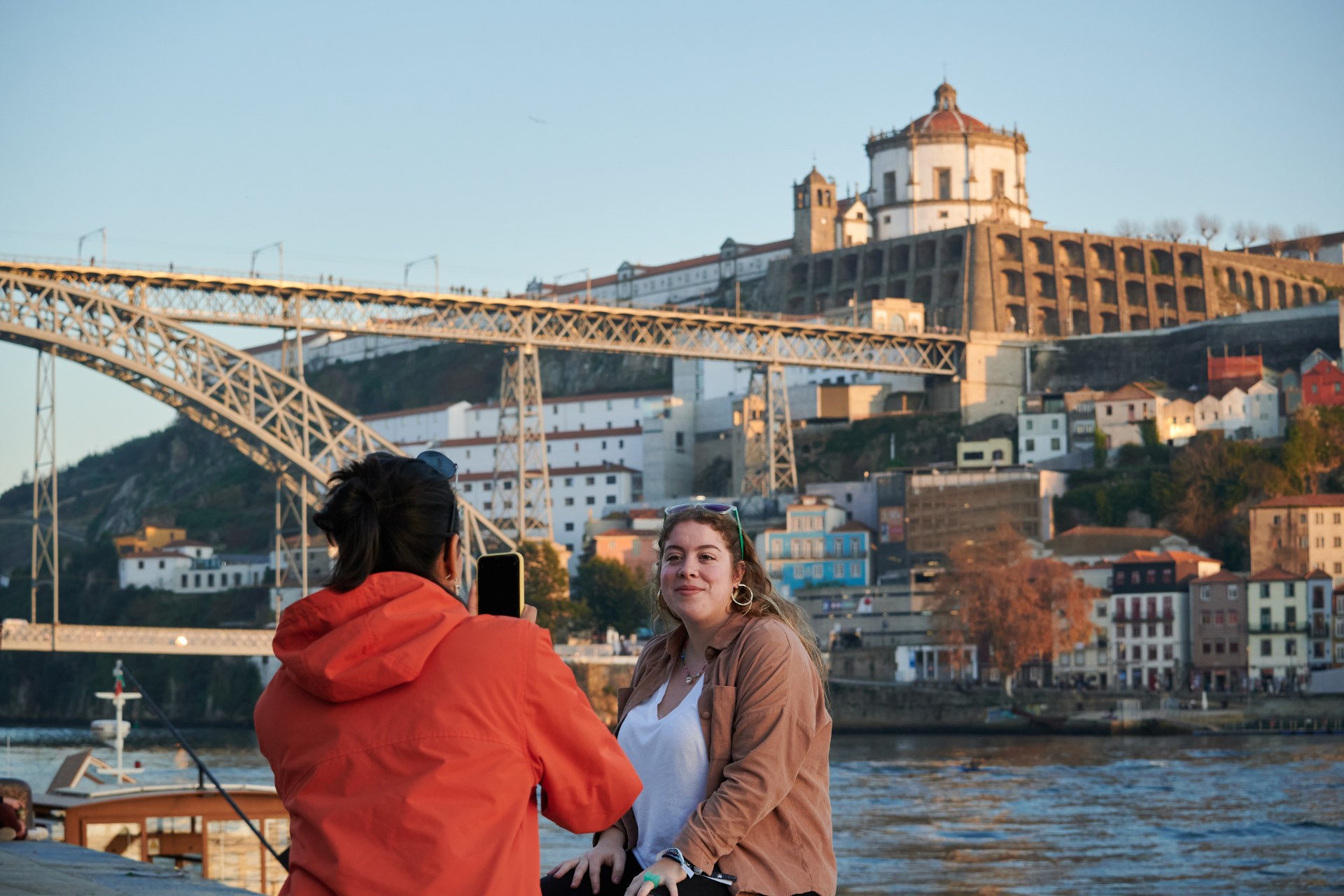 Una joven fotografía a su amiga con un puente de Oporto al fondo